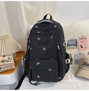 Detail of black school backpack featuring white bow print and functional side buckles