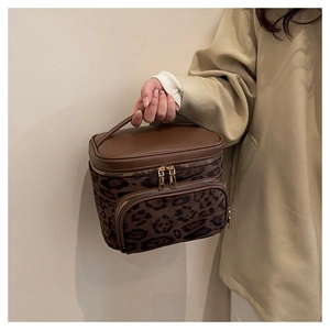 Macro detail of brown leopard print makeup bag with gold zipper and faux suede texture