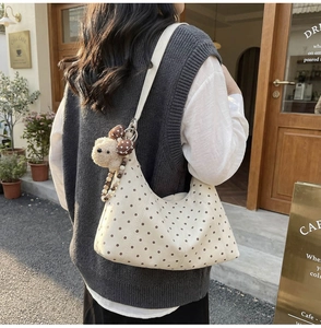 Chic beige polka dot crescent bag with a cute bear plush keychain detail