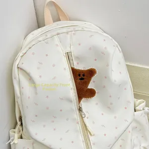 Detail of the large front pocket on an off-white backpack with pink star patterns