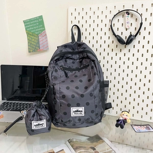 Detailed set of grey polka dot backpack and matching drawstring bag on a desk