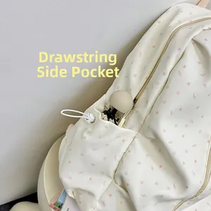Detail view of the drawstring side pocket on a cream canvas backpack with star patterns