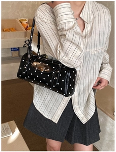 Polka dot cylindrical handbag featuring glossy texture and metallic lock detail