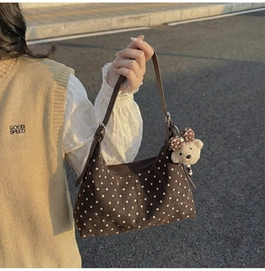 Detail of vintage brown polka dot crossbody bag with a plush bear charm and bow decoration