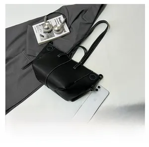 Detail view of black lychee grain leather tote bag with white contrast stitching