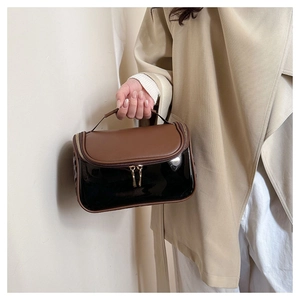 Detail of a dual-tone PU leather cosmetic bag with gold zippers and a top handle