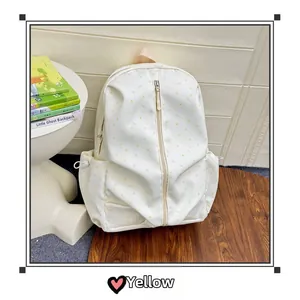 Detail of a creamy white backpack featuring yellow star patterns and vertical zipper pocket
