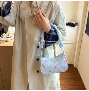 Detail of light blue seersucker bag with floral patterns and red bow accents