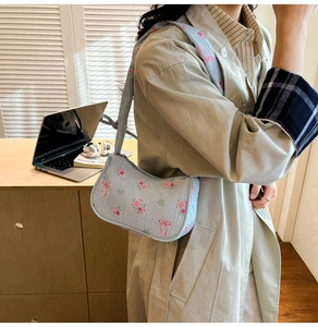 Detailed texture of light blue floral canvas hobo bag with pink bow pattern and strap