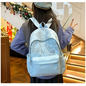 Detail of light blue backpack with moon and star prints worn by a model in a cozy indoor setting