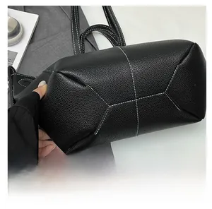 Close-up of contrast stitching on the base of a black lychee pattern leather tote bag