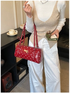 Detail of red polka dot cylinder handbag with bow shoulder strap and metallic branding