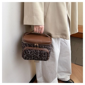 Detail view of leopard print vanity bag with leather handle and golden zipper hardware