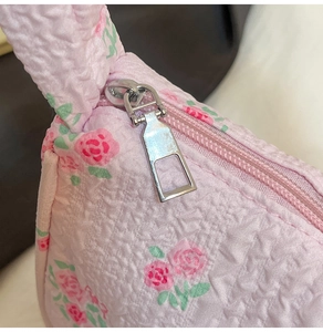 Detailed view of silver metal zipper and textured pink floral canvas on women's bag