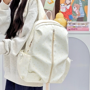 Detail of a beige star-patterned backpack showing side pockets and drawstring closure