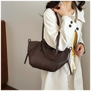 Detail view of brown leather tote bag with white contrast stitching and drawstring decor