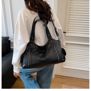 Detail of a large black lychee leather tote with silver zippers shown on a model