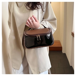 Detail view of the brown leather top and black glossy finish of the travel cosmetic bag