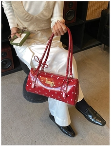 Detail of red cylindrical shoulder bag with white polka dots and silver heart padlock