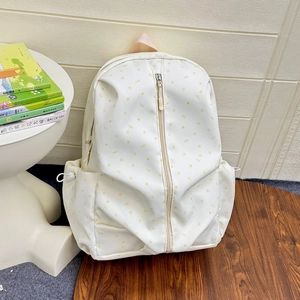 Close-up of cream white school backpack with yellow stars and vertical zipper detail