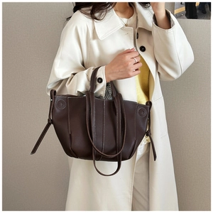 Detail of dark brown pebble leather tote bag with white contrast stitching and side drawstring