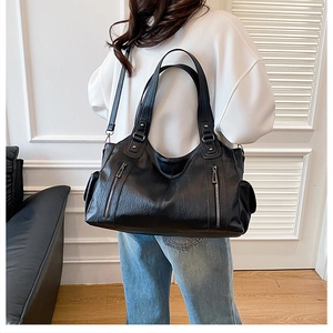 Detail of black leather tote bag with vertical zippers and adjustable shoulder strap
