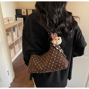 Detail of vintage brown polka dot hobo bag with a plush bear charm on a female model