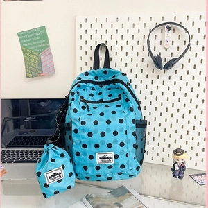Vibrant blue polka dot backpack set with matching drawstring bag on a white desk setup