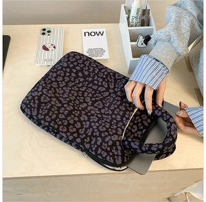 Detail of leopard print laptop sleeve with reinforced handle and dual zipper closure