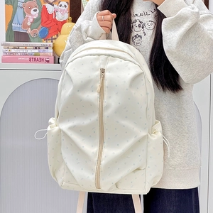 Detail of white backpack with blue stars, vertical zipper, and drawstring side pockets