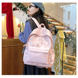Pink casual backpack with moon and star prints worn by a model in a festive setting