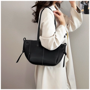 Close-up of black tote bag featuring white contrast stitching and side knot detail