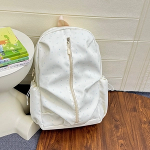 Detailed view of white backpack with blue star patterns and vertical front zipper