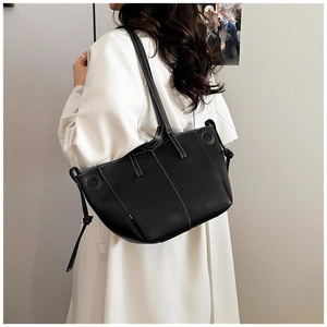 Detail of black tote bag with white contrast stitching and decorative side knots