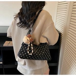 Detailed close-up of a black polka dot crossbody bag featuring a plush bear and bead charm