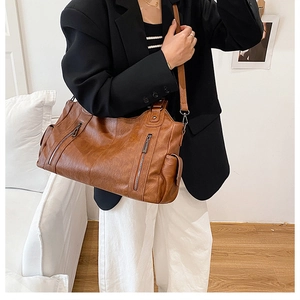 Detailed view of brown PU leather tote bag featuring stylish vertical metal zippers