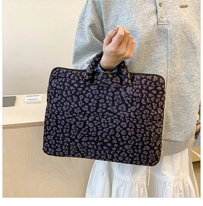 Detailed macro view of purple leopard print laptop bag with metallic double zippers