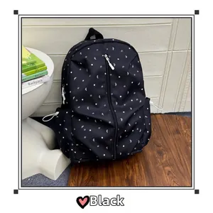 Detail of black starry school backpack featuring white star patterns and front zip pocket