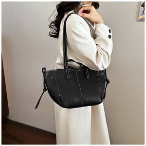 Detailed view of black lychee leather tote bag featuring white contrast stitching and side knots