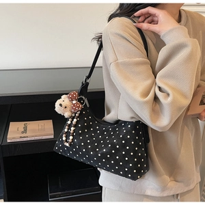 Polka dot shoulder bag with cute bear charm and bead detail worn over the shoulder
