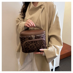 Detail of leopard print vanity case with brown leather trim and metal dual zippers