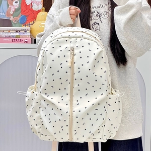 Detail of canvas backpack featuring black star prints and vertical zipper closure