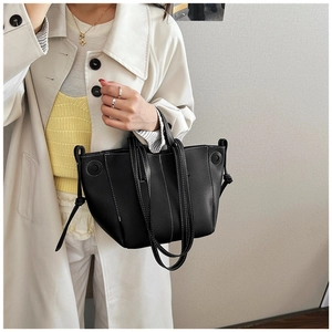 Close-up of black litchi leather tote with white contrast stitching and dual straps