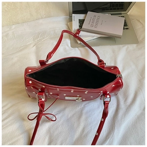 Detail view of red polka dot leather Boston bag with side ribbon bow and silver hardware