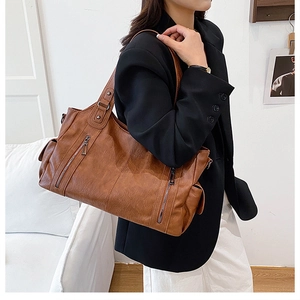 Detail view of a large brown vintage tote bag featuring multiple functional zipper pockets