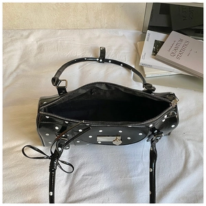 Close-up of black polka dot shoulder bag with silver hardware and chic bow charm on bed