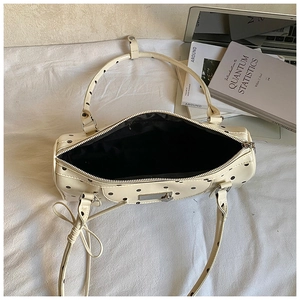 Chic cream Boston bag with black polka dots, top handles, and adjustable shoulder strap