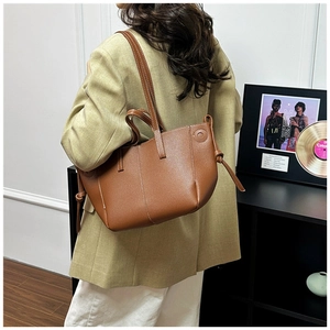 Close-up of brown textured leather tote bag with white contrast stitching and drawstring