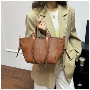 Close-up of brown litchi pattern leather tote bag with contrast stitching and side knot