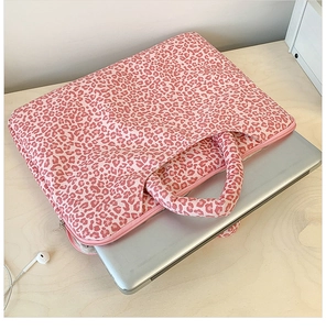 Pink leopard print laptop tote bag with zipper closure shown on a light wooden desk